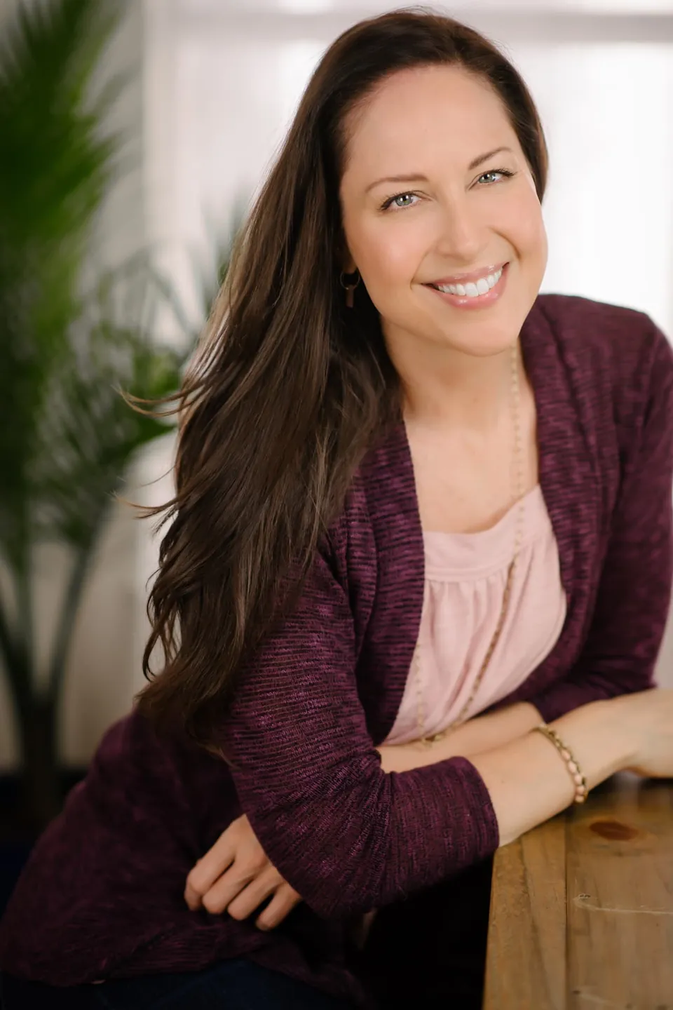 Alyssa Malehorn smiling, seated beside a wooden table
